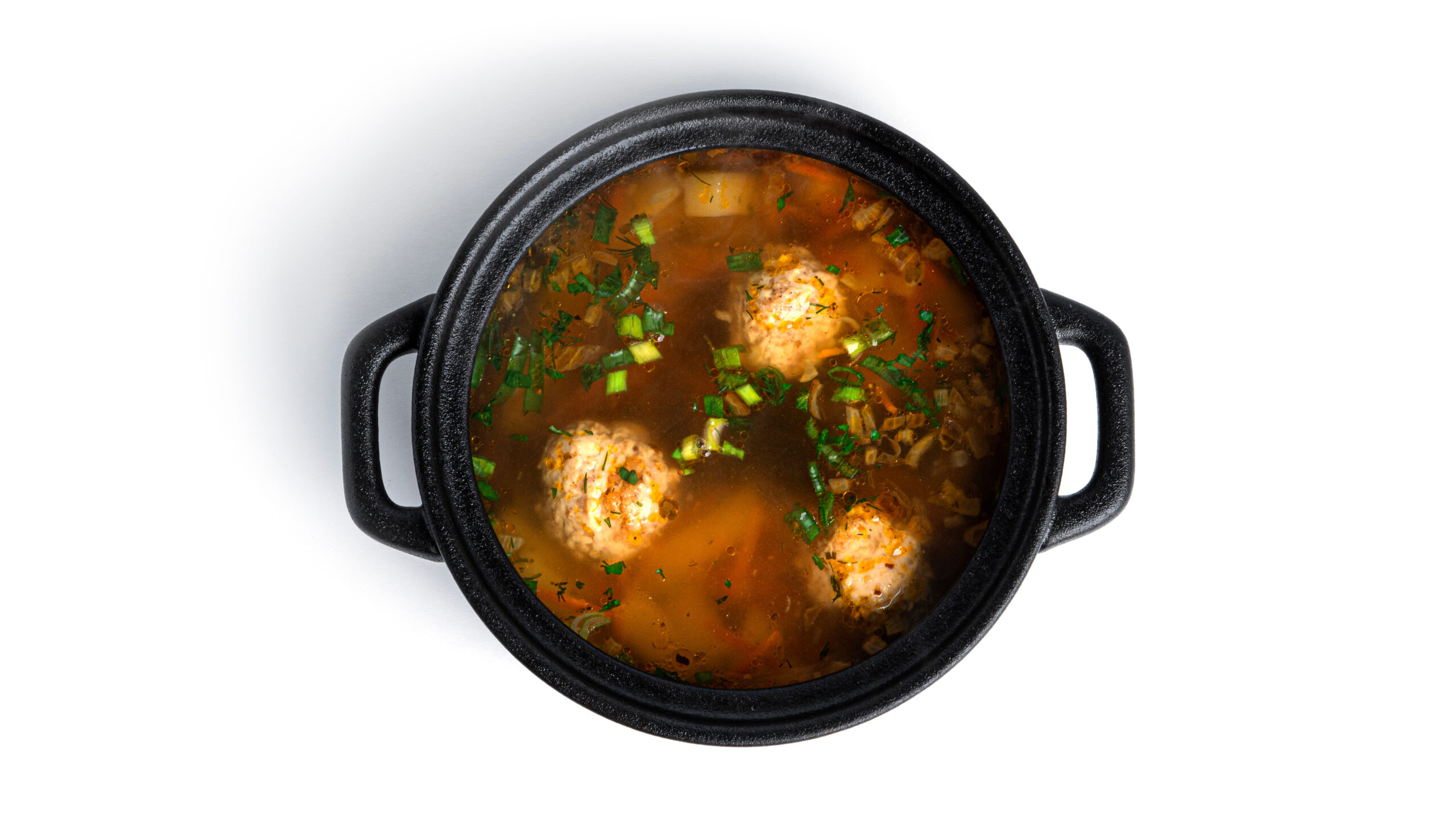 Soup with meatballsi n a black pot isolated on a white background. High quality photo